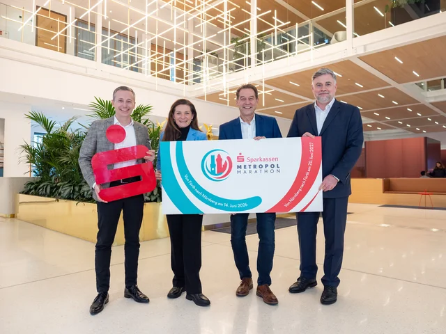 Die genannten Personen stehen mit einem Schild des Metropolmarathons und einem Sparkassen-Logo nebeneinander. Klick öffnet die Meldung.