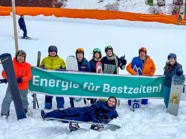 Gruppenfoto von Teilnehmenden mit einem Banner des Sponsors infra mit dem Text "Energie für Bestzeiten" Klick öffnet die Meldung.
