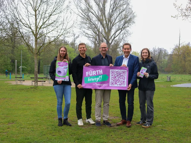 Das Foto zeigt die genannten Personen. Sie stehen auf der Wiese vor der Siebenbogenbrücke und halten ein Plakat mit der Aufschrift "Fürth bewegt". Klick öffnet die Meldung.