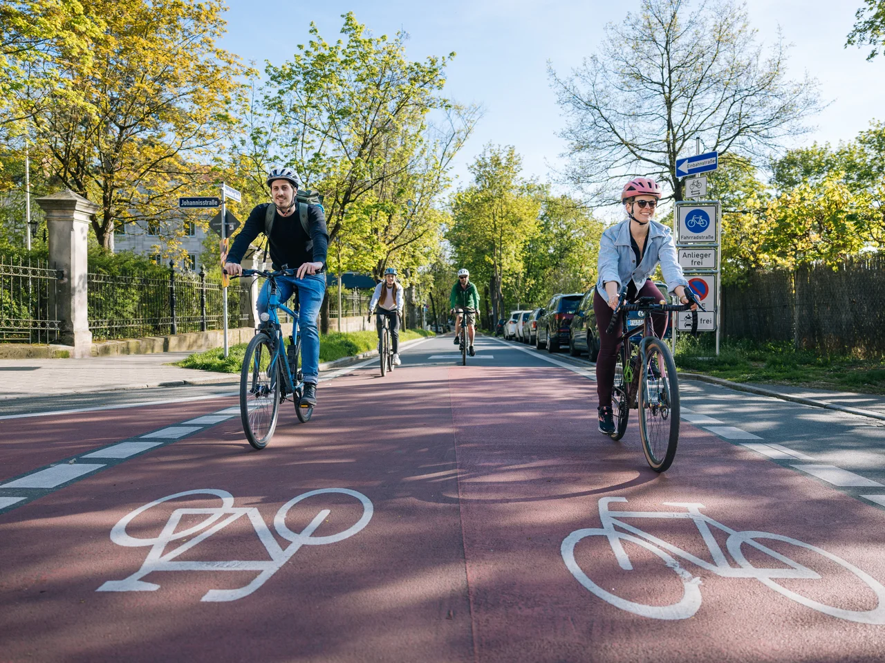 Mehrere Personen befahren die Fahrradstraße Dambacher Straße an einem sonnigen Tag.