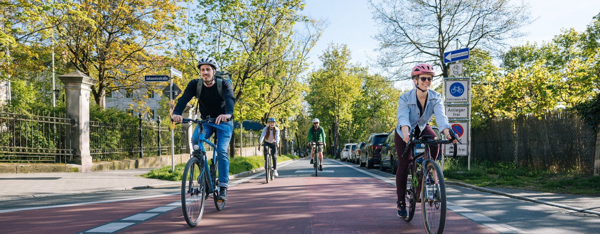 Mehrere Personen befahren die Fahrradstraße Dambacher Straße an einem sonnigen Tag.