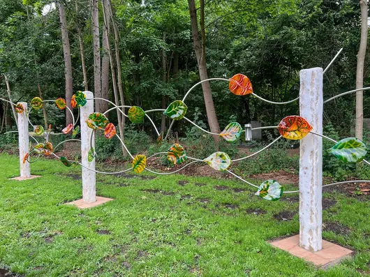 Handgefertigte, bunte Glasblätter, die durch gebogene Edelstahlrohre verbunden sind. Klick öffnet die Meldung.