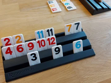 Spielsteine des Spiels Rummikub in einem schwarzen Spielhalter auf einem Holztisch