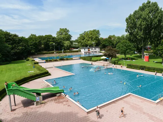 Außenbereich des Sommerbad Fürth mit Rutsche, Becken und Badegästen Klick öffnet die Meldung.