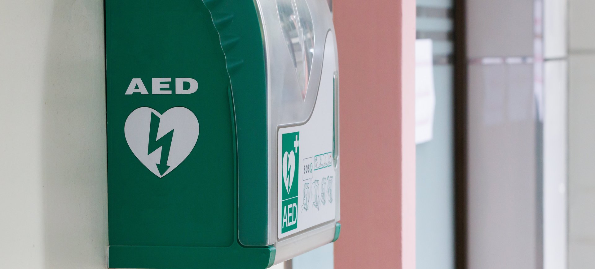 Automated external defibrillator in green box hang on wall in hospital. AED medical first aid device. Defibrillator hängt an einer Wand.