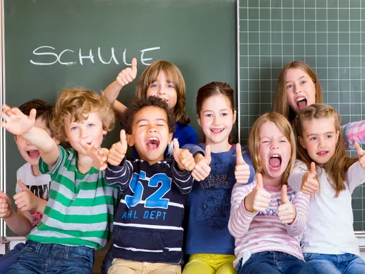 Eine Gruppe ausgelassener Schulkinder vor einer Schultafel.