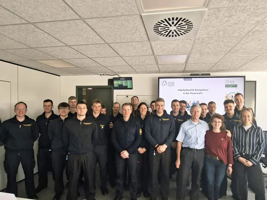 Gruppenfoto mit allen Teilnehmenden am Workshop vor einem großen Bildschirm in einem Besprechungsraum. Klick öffnet die Meldung.
