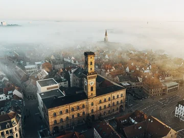 Luftaufnahme des Fürther Rathaus bei Nebel, im Hintergrund der Kirchturm von St. Michael, umgeben von Häusern und Straßen.