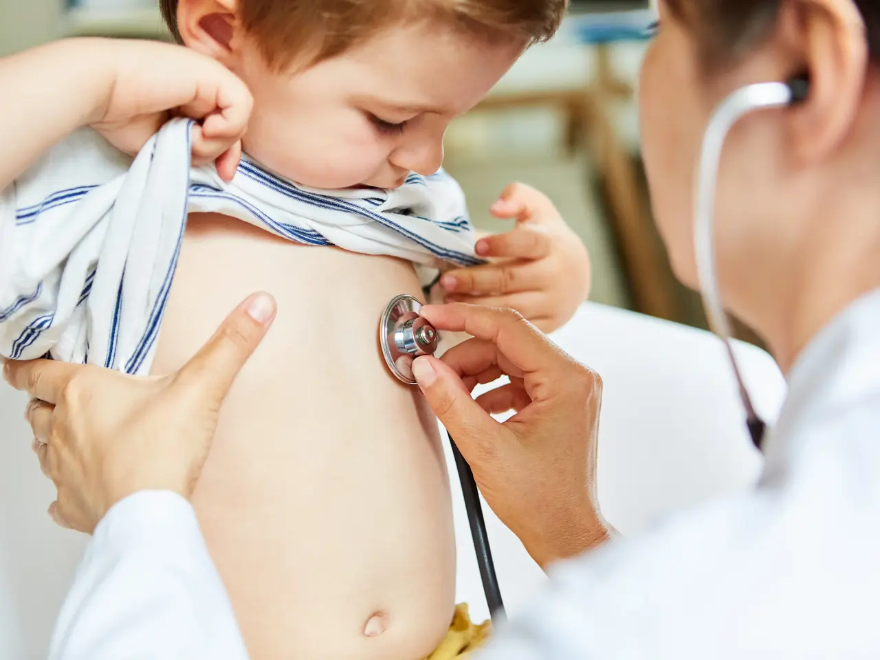 Kinderärztin beim Abhören einer Lunge vom Kind mit Stethoskop. Klick öffnet Bild in größerer Ansicht.