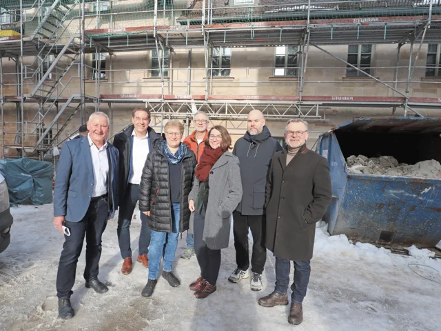 Genannte Personen vor dem eingerüsteten Altbau Klick öffnet die Meldung.