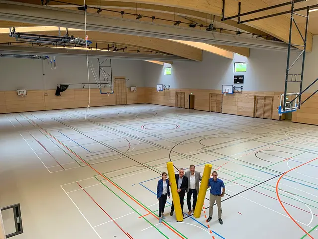 Jung, Lippert, Braun und Stiegler stehen inmitten der neuen, in rund fünf Meter Tiefe eingelassenen Dreifachturnhalle mit gebogenem Gründach.