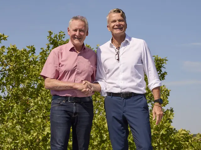 Jung im roten Hemd beim Handshake Bedall im weißen Hemd auf dem Dach der Schule. Klick öffnet die Meldung.