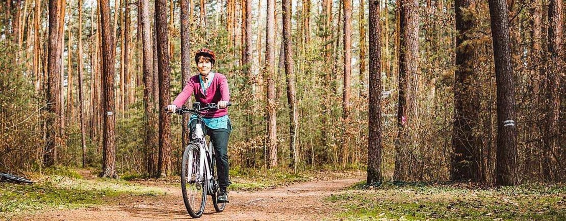 Freizeitmöglichkeiten im Stadtwald Eine Frau fährt auf dem Fahrrad durch den Stadtwald