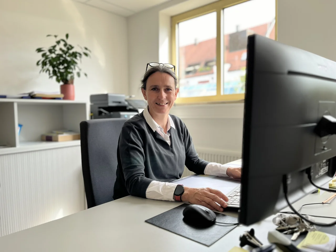 Koordinatorin Sylvie Lamotte sitzt an ihrem Schreibtisch und lächelt in die Kamera.