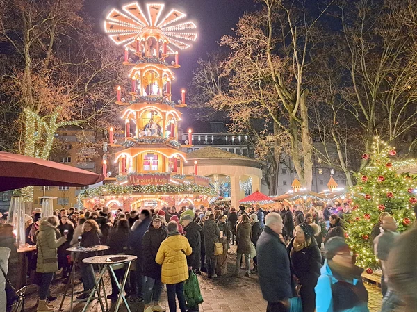 Pyramide auf dem Weihnachtsmarkt mit Menschen. Klick macht Bild größer.