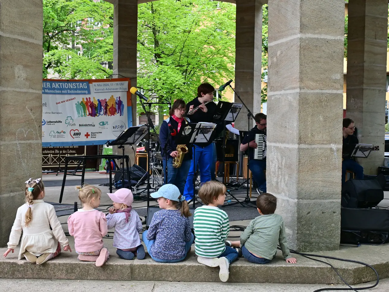 Kinder lauschen einer Band am Pavillon in der Konrad-Adenauer-Anlage. Klick öffnet Bild in größerer Ansicht.