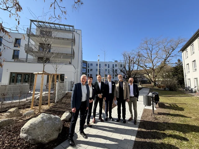 Auf dem Bild stehen die genannten Personen im Innenhof und im Hintergrund sind sowohl der Neubau des ehemaligen Stiftungsaltenheims sowie die beiden bestehenden alten Gebäude zu sehen. Klick öffnet die Meldung.