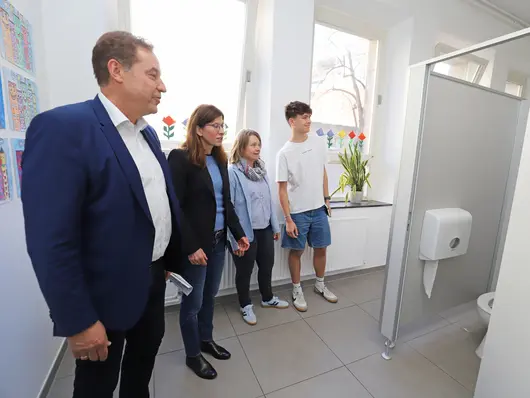 Personen in der sanierten Sanitäranlage; Klick zeigt Bild in größerer Darstellung.