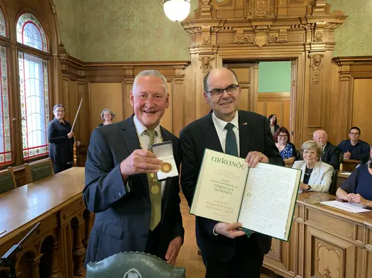 Oberbürgermeister Jung und Christian Schmidt bei der feierlichen Verleihung im großen Sitzungssaal des Rathauses. Jung zeigt die Medaille, Schmidt die Urkunde. Klick öffnet die Meldung.