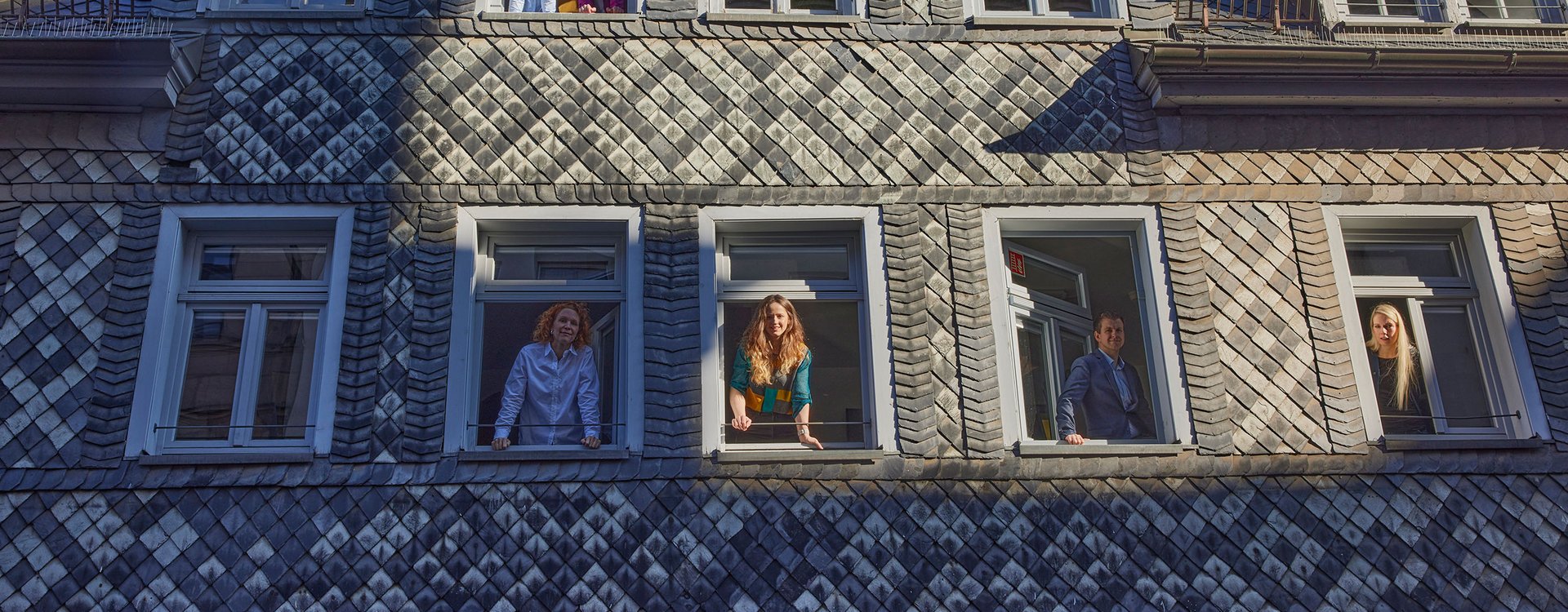 Die Fassade in der Gartenstraße. Die teammitglieder des Instituts schauen aus den Fenstern. 