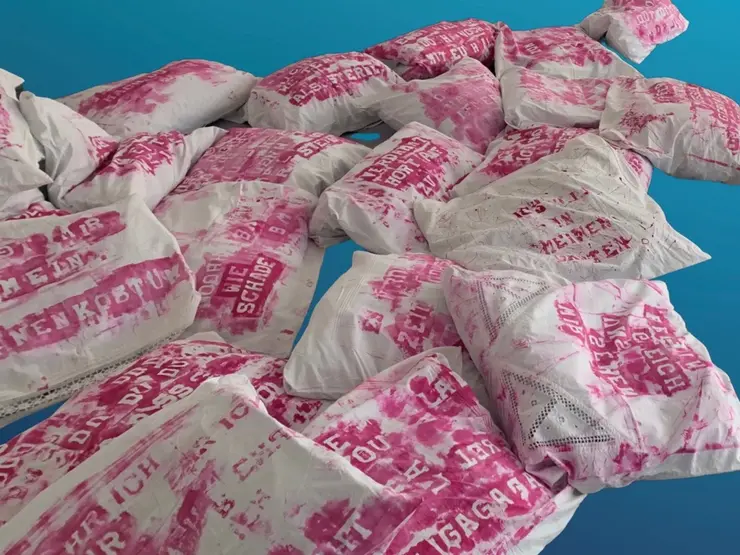 Foto von mehreren Spitzenkissenbezügen bedruckt mit pinker Schrift