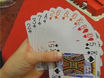 Hand hält Fächer aus Spielkarten mit verschiedenen Farben und Symbolen