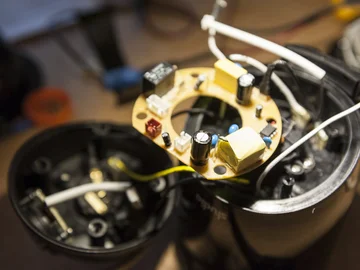 Nahaufnahme einer geöffneten elektronischen Vorrichtung mit sichtbarer runder Leiterplatte und Bauteilen