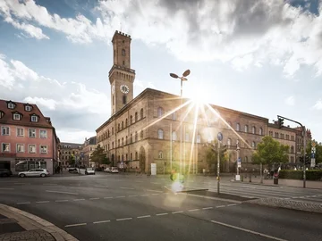 Das Rathaus von Fürth mit hohem Turm bei Sonnenlicht, umgeben von Straßen und Gebäuden in der Innenstadt.