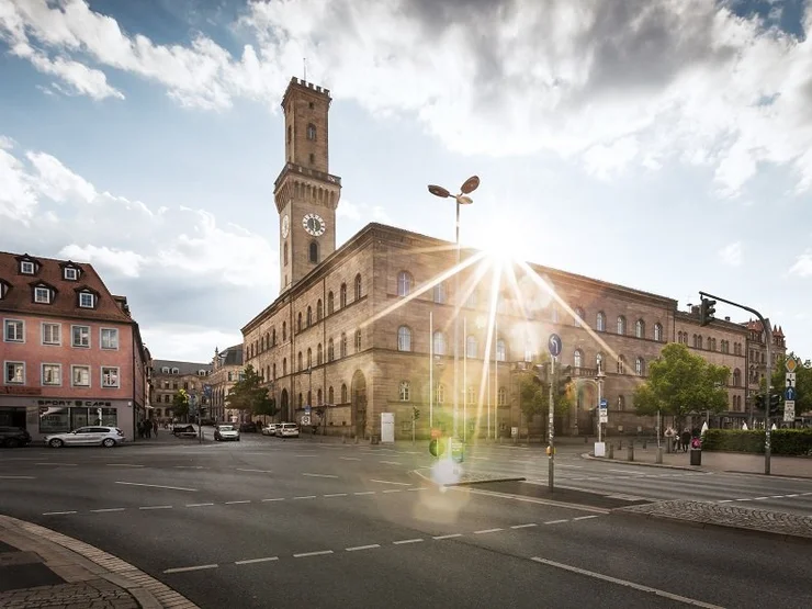 Das Rathaus von Fürth mit hohem Turm bei Sonnenlicht, umgeben von Straßen und Gebäuden in der Innenstadt.