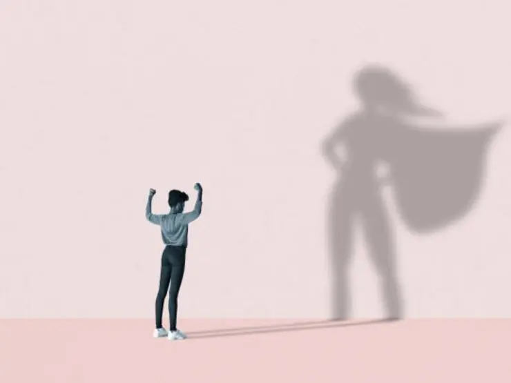 Junge Frau zeigt ihre Muskeln und wirft einen Schatten, bei sie als Super-Woman erscheint.