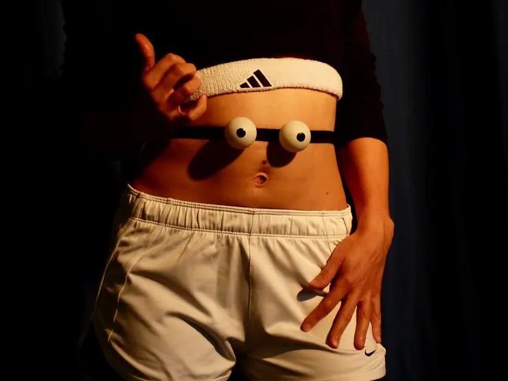 Sportliche Person mit einem weißen Adidas-Band um die Taille, darunter zwei große, runde Augen an einem Gummiband.