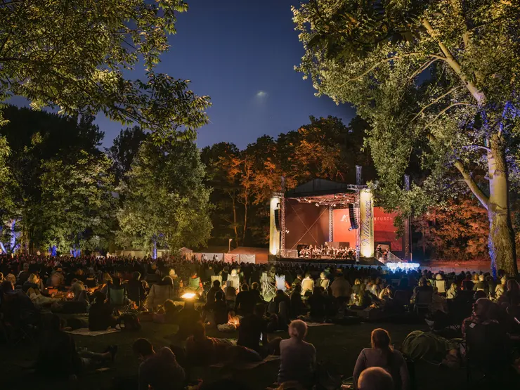 Publikum vor der Bühne im nächtlichen Stadtpark; Klick öffnet Veranstaltungstipp