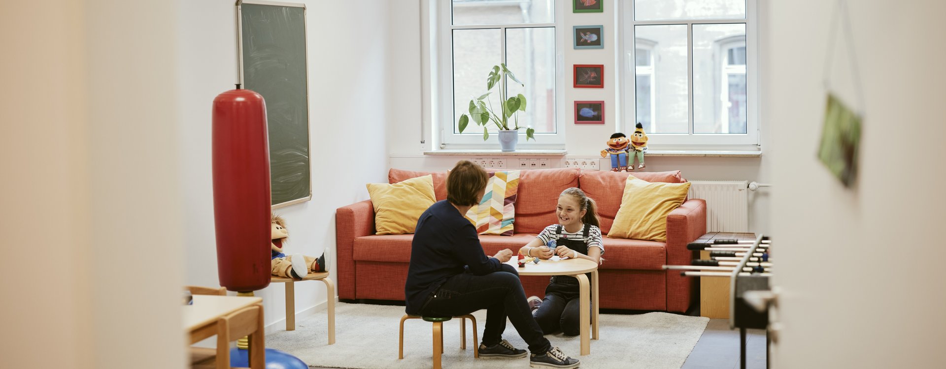 Räumlichkeiten der Jugend- und Familienberatung Blick in einen freundlich eingerichteten Raum, in dem eine Frau mit einem Kind spricht.