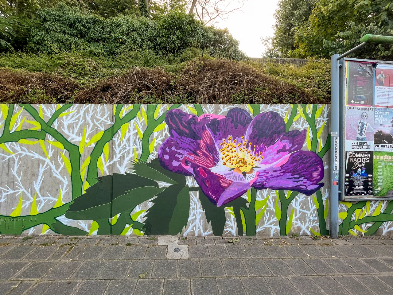 "Um dieser"Rose Willen" ist der Titel des Werkes von Guy Palumbo, das eine violette Rose an einer etwa ein Meter hohen Betonwand zeigt. 
