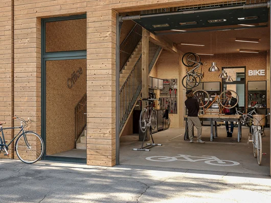 Illustration einer Halle, in der eine Fahrradwerkstatt untergebracht ist. Klick öffnet die Meldung.