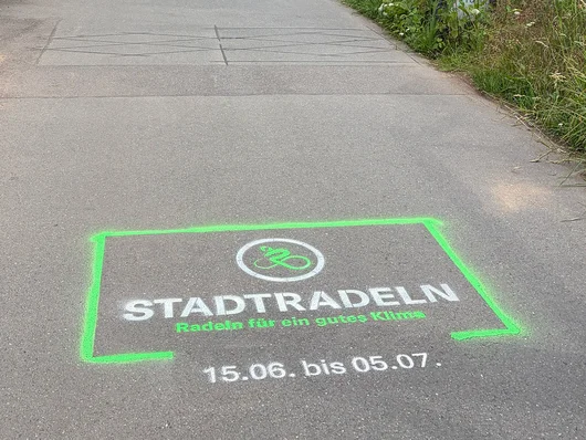 Radweg mit aufgespraytem Logo mit der Aufschrift "Stadtradeln. Radeln für ein gutes Klima. 15.6. bis 5.7." Klick öffnet die Meldung.