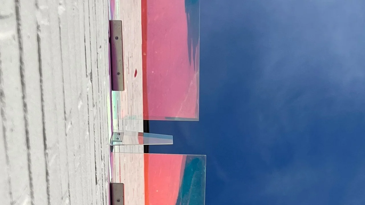 Mehrere farbige, transparente Plexiglasplatten an Hausfassade vor blauem Himmel