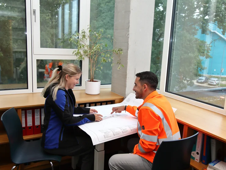 Zwei Mitarbeitende sitzen gemeinsam an einem Tisch und besprechen sich. 