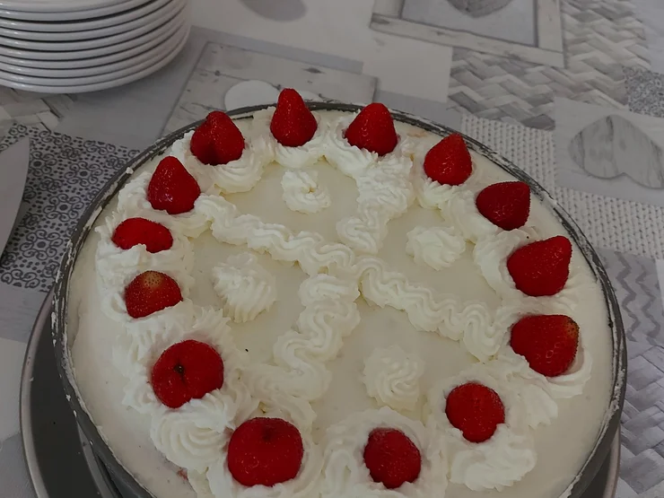 Runde Torte mit weißer Sahne und Erdbeeren als Dekoration auf einem Tisch