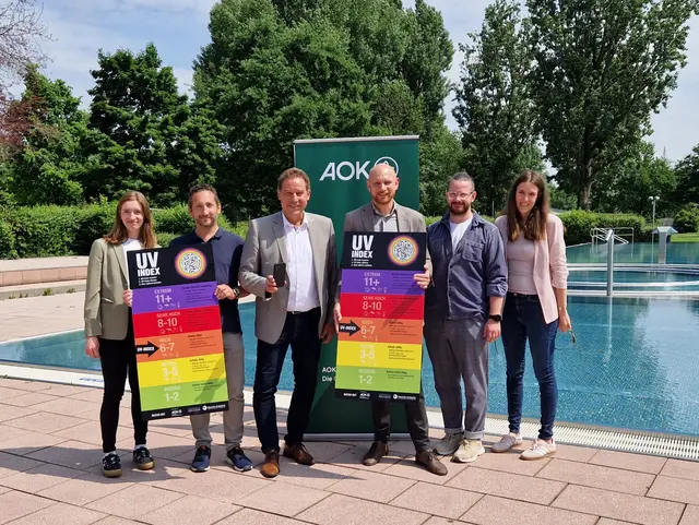Gruppenfoto vor einer UV-Index-Tafeln im Sommerbad Scherbsgraben; Klick zeigt Bild in größerer Darstellung. 