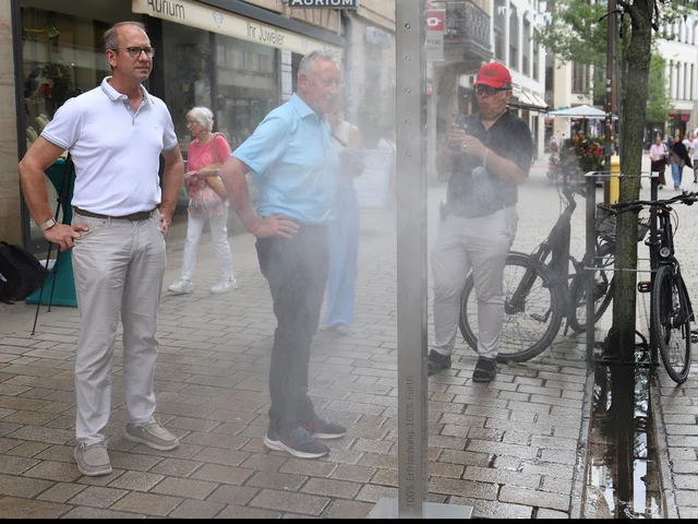 Genannte Personen stehen neben der Säule, die gerade Wassernebel versprüht. Klick öffnet die Meldung.