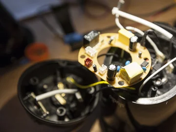 Nahaufnahme einer geöffneten elektronischen Vorrichtung mit sichtbarer runder Leiterplatte und Bauteilen