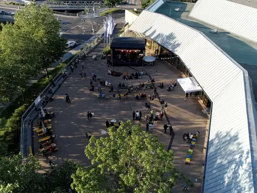 Personen feiern auf der Uferterrasse. Klick öffnet Veranstaltungstipp.