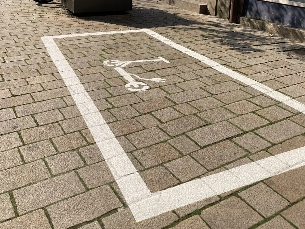 Weiße Bodenmarkierung mit einem weißen E-Scooter-Piktogramm.