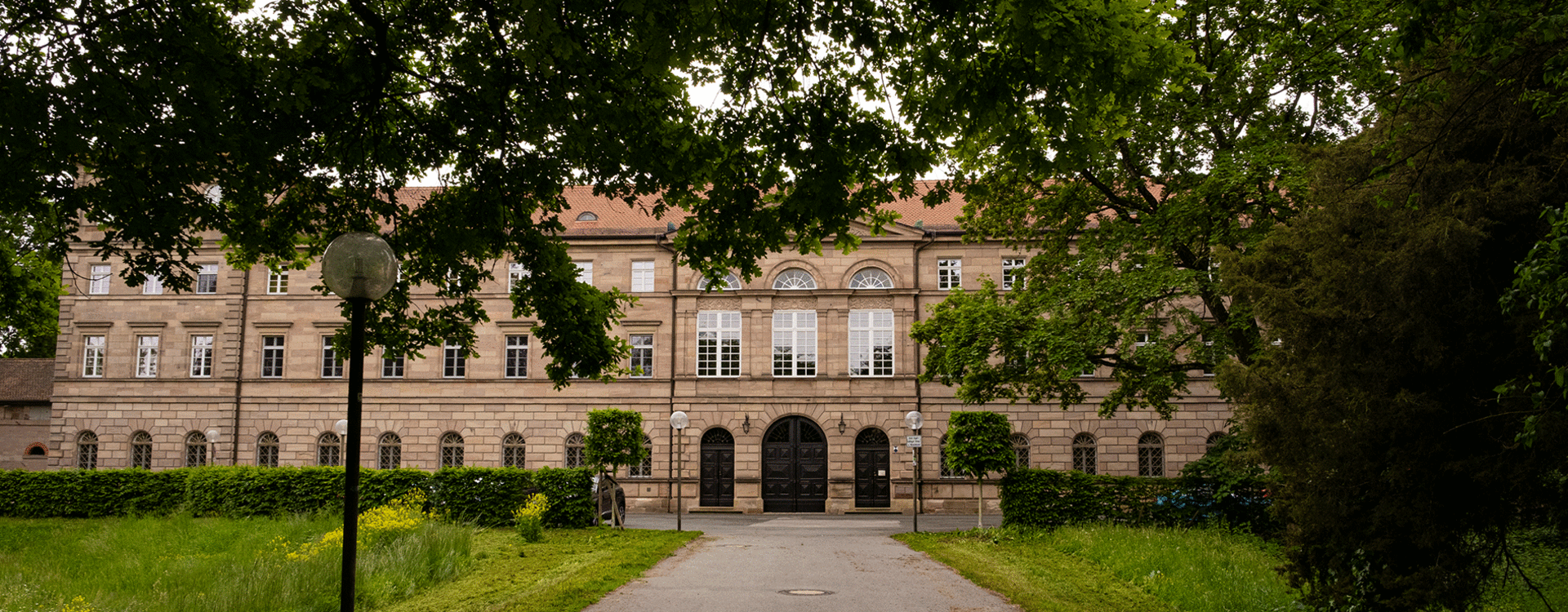 Blick durch den Park auf den Haupteingang von Schloss Burgfarrnbach