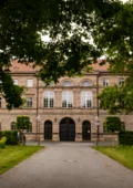 Blick durch den Park auf den Haupteingang von Schloss Burgfarrnbach
