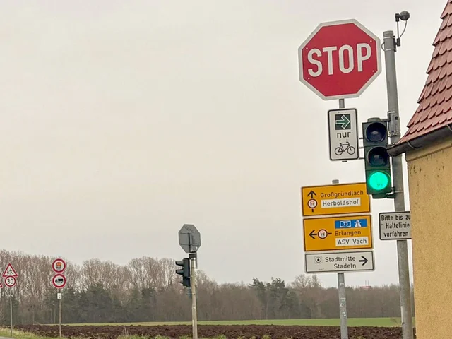 Grün leuchtende Ampel mit grünem Pfeil und Fahrradpiktogramm unter rotem Stoppschild an einer Kreuzung. Klick öffnet die Meldung.