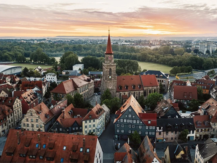 Luftaufnahme der Altstadt mit der Kirche St. Michael im Zentrum, umgeben von historischen Fachwerkhäusern bei Sonnenuntergang.