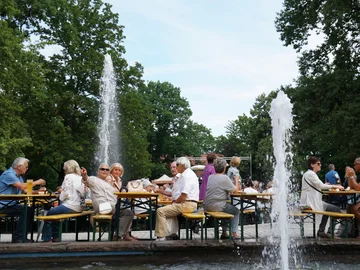 Personen sitzen an Biertischen am Fontänenhof