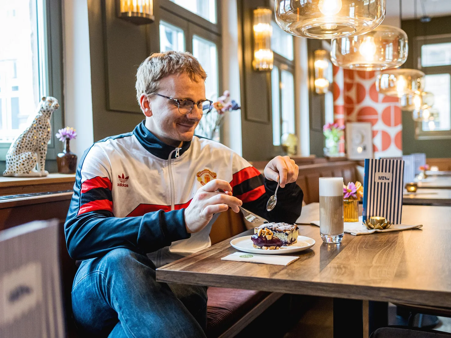 Junger Mann in einem hübschen Cafe genießt ein Stück Kuchen.